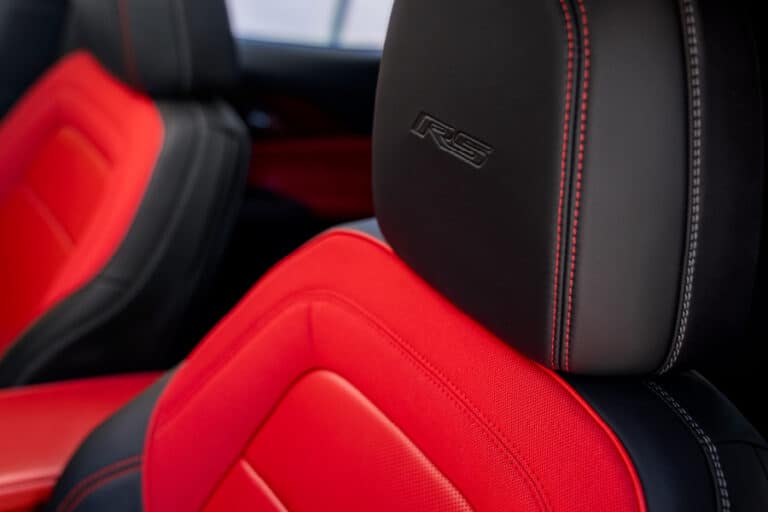 Close-up view of luxury car seats featuring a combination of black and red upholstery, highlighting the RS logo on the headrest, showcasing vibrant design and premium materials for enhanced comfort and style.