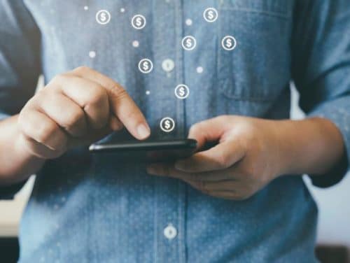 Person interacting with a smartphone, with dollar signs graphic overlay suggesting mobile financial transactions or online shopping.