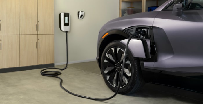 Electric vehicle charging in a modern garage, showcasing a plugged-in electric car with charging station mounted on the wall. The image highlights eco-friendly transportation and home charging convenience.