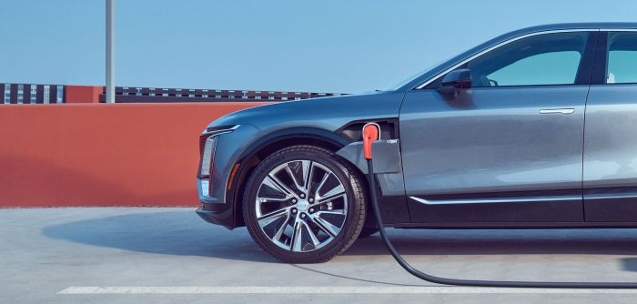 Electric vehicle charging in a modern garage, showcasing a plugged-in electric car with charging station mounted on the wall. The image highlights eco-friendly transportation and home charging convenience.