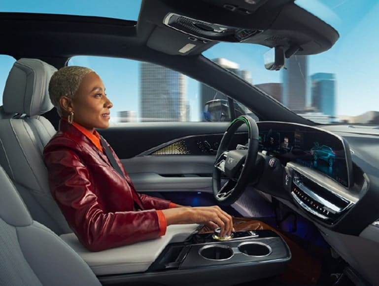 Woman driving a modern vehicle with a city skyline in the background, showcasing OnStar connected feature