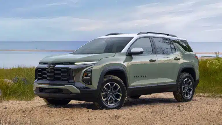 Chevrolet SUV in green parked by the beach with grassy dunes and ocean in the background