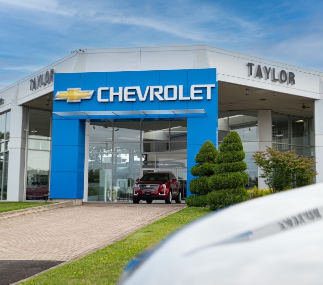 Front view of the Taylor AutoMall Chevrolet dealership building with glass windows, blue Chevrolet sign, and landscaping
